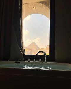 a bathroom sink with a window with a view of the pyramids at Zahira Pyramids View in Cairo