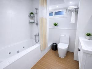 a white bathroom with a toilet and a sink at Hotel Asia Pacifico in Santiago