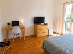 a bedroom with a bed and a desk with a television at Chambre Lac Rose in Lausanne