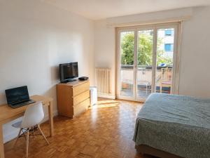 a bedroom with a bed and a desk and a television at Chambre Lac Rose in Lausanne