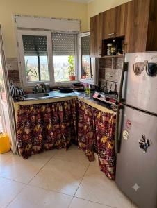 a kitchen with a refrigerator and a counter with curtains at Dar mouni relax in Oran