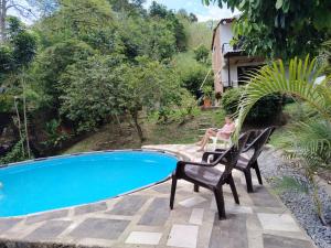 a person sitting on a chair next to a pool at Casa en el campo - villeta in Villeta