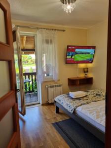a bedroom with a bed and a tv on the wall at Gościniec Joanna in Rajgród