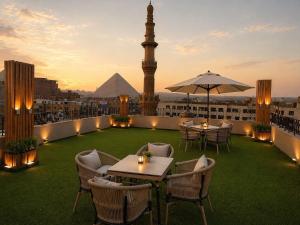 a rooftop patio with tables and a mosque in the background at Horizon Pyramids Boutique in Cairo