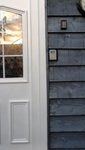 a white door with a window next to a house at Robins nest in Great Hanwood