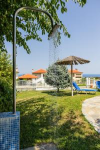 a park with a fountain and a chair and an umbrella at Zeusplace Anamesa Pool Villa in Litochoro