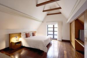 a bedroom with a white bed and a television at Hotel bh La Quinta in Bogotá