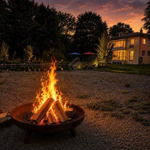 a fire pit with a book in it at sunset at Villa Kirnach Private Spa Retreat im Allgäu in Biessenhofen