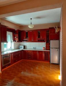 a kitchen with red cabinets and a wooden floor at Family-friendly in Pogradec