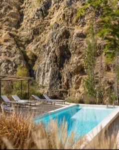 a swimming pool with lounge chairs and a mountain at Glaciar de Roca Lofts in Horcon