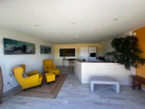 a living room with yellow chairs and a kitchen at Hillside House Residence in Foz do Arelho