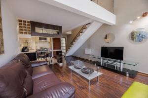a living room with a leather couch and a tv at SINGLE RENT'APARTMENT in Concepción
