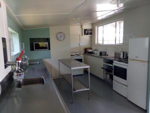 a kitchen with white appliances and a table in it at Leithfield Beach Holiday Park in Leithfield +46 photos