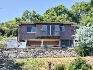 a house with a stone wall at Kingfisher Lodge in Shodoshima