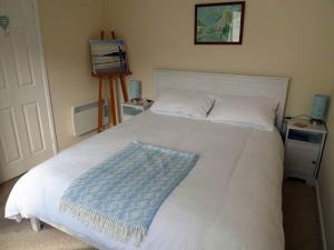 una camera da letto con un letto bianco con una coperta blu sopra di Riverbella a Looe