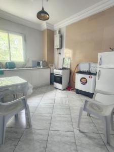 a kitchen with white appliances and a table and chairs at Location saisonnière entre mer, forêt et calme in Raʼs al Jabal