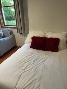 a white bed with a red pillow on it at Cabernet Sauvignon Escape in Calgary