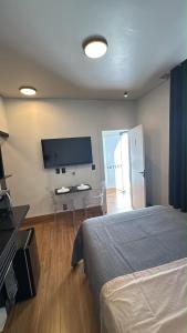 a bedroom with a bed and a desk and a tv at 1Studio ao lado da Praça Augusto Silva, PRÓXIMO À UFLA E UNILAVRAS in Lavras