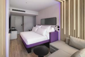 a bedroom with a white bed and a couch at YOTEL Bangkok Sukhumvit in Ban Nong Chaeng