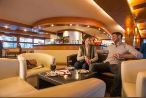 a man and woman sitting on a couch in a restaurant at Belambra terra nova in La Plagne Tarentaise