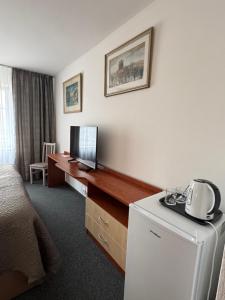 a hotel room with a bed and a desk with a refrigerator at Park Pension in Nové Benátky