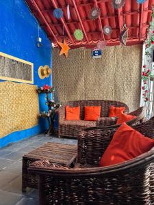 a room with wicker chairs and a table with orange pillows at Capitolio 02 in Canoa Quebrada
