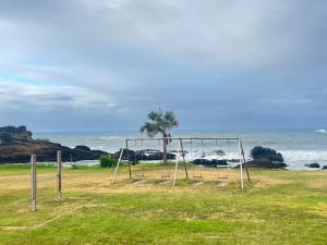 an empty swing set by the ocean with a palm tree at 海岸道路沿い 磯の宿 in Minamiboso