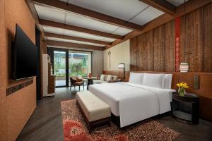 a bedroom with a large white bed and a living room at Hotel Indigo Nalati by IHG in Narat