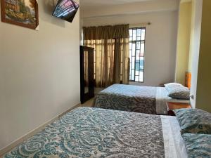 a hotel room with two beds and a window at Hostal acacias in Cuenca
