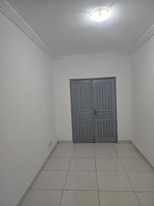 a room with a door in the middle of a white room at Chambre simple in Libreville