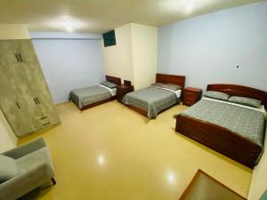 a room with three beds and a chair in it at Hostal acacias in Cuenca