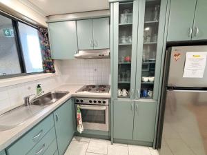 a kitchen with green cabinets and a sink and a refrigerator at Northpoint Apartment 5 - Bring your own linen. in South West Rocks +7 photos