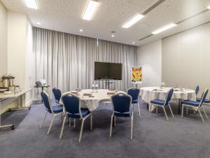 a conference room with two tables and chairs and a screen at Pullman Liverpool in Liverpool
