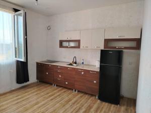 a kitchen with a black refrigerator and wooden cabinets at gulelebi in Tʼianetʼi