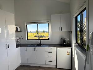 a white kitchen with a sink and a window at Hanger Ridge Cabin in Goodger
