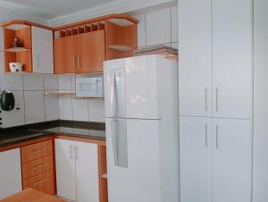 a kitchen with a white refrigerator and wooden cabinets at LOFT NOVO CONFORTÁVEL in Sorocaba +43 photos