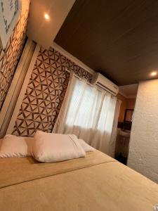 a bedroom with a large bed with a window at Angel Hospedagem de quartos Self Check in in Vila Velha