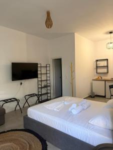 a bedroom with a large white bed with a flat screen tv at Coconut beach villas 4 in Schinias