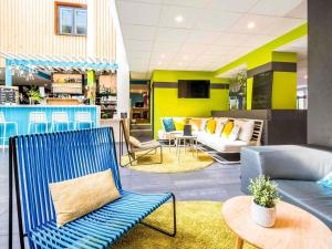 a lobby with a blue chair and a couch at Ibis Styles Toulouse Labège in Labège