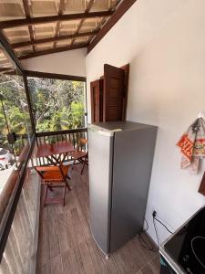 a kitchen with a refrigerator and a table on a balcony at Agradável Kitnet próximo à Praia do Forte in Mata de Sao Joao