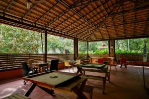 a dining room with tables and chairs and windows at Kadkani River Resort Coorg in Siddapur