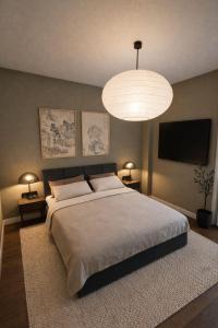 a bedroom with a large bed and a large chandelier at A1 HighTown Aprtmnt, Steps frm Luton Train Station in Luton