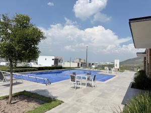 a swimming pool with chairs and a table next to a building at Bello departamento iluminado ideal para descansar in Querétaro
