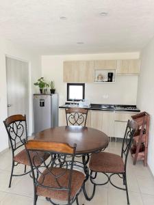 a kitchen with a table and chairs and a refrigerator at Bello departamento iluminado ideal para descansar in Querétaro