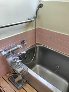 a stainless steel tub in a bathroom with pink tiles at Kingfisher Lodge in Shodoshima