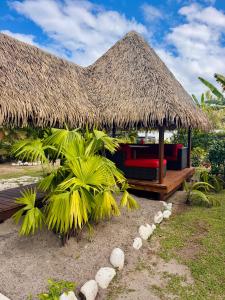 a straw hut with a bench and palm trees at Vanakea Beach House, accès privé plage PK18 in Punaauia