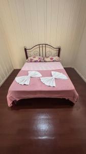 a bed with a pink blanket and two pillows at Casa no Centro in Campo Largo