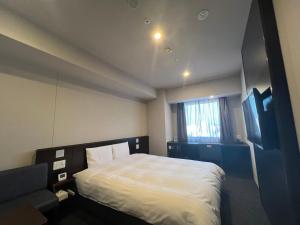 a bedroom with a bed and a flat screen tv at Dormy Inn Kochi in Kochi +45 photos