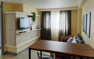 a living room with a table and a television at Ambassador Residence Apart-hotel in Curitiba