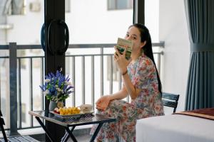 a woman sitting on a chair drinking a cup of coffee at Pi Hotel Phố cổ Hoa Lư in Kỳ Vĩ